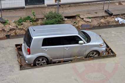 VIDEO Un șofer a lăsat mașina pe o stradă care urma să fie asfaltată. Muncitorii au acoperit-o cu folie și au turnat ciment în jurul ei